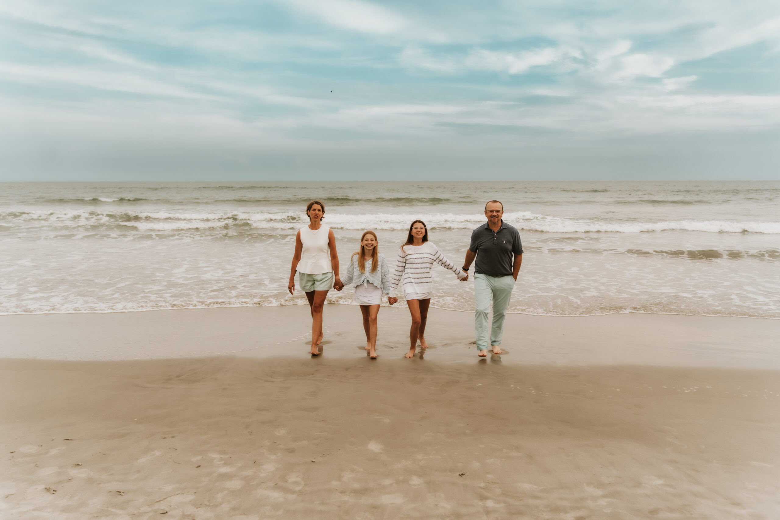 Family walking along the shoreline during sunset in Myrtle Beach during photo session