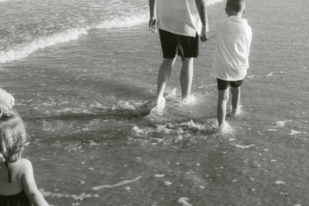 amily with young kids splashing in Charleston SC beach waves during photoshoot by Moody Momma photographer