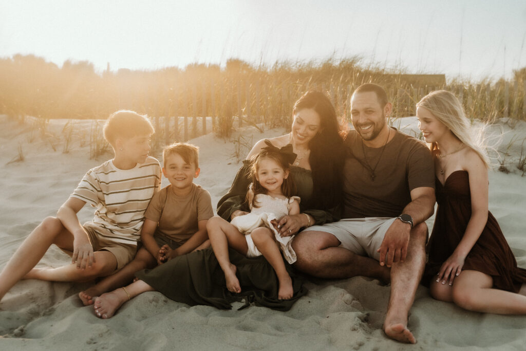Family group hug in grassy dunes at Myrtle Beach SC during golden hour photoshoot by Moody Momma photographer