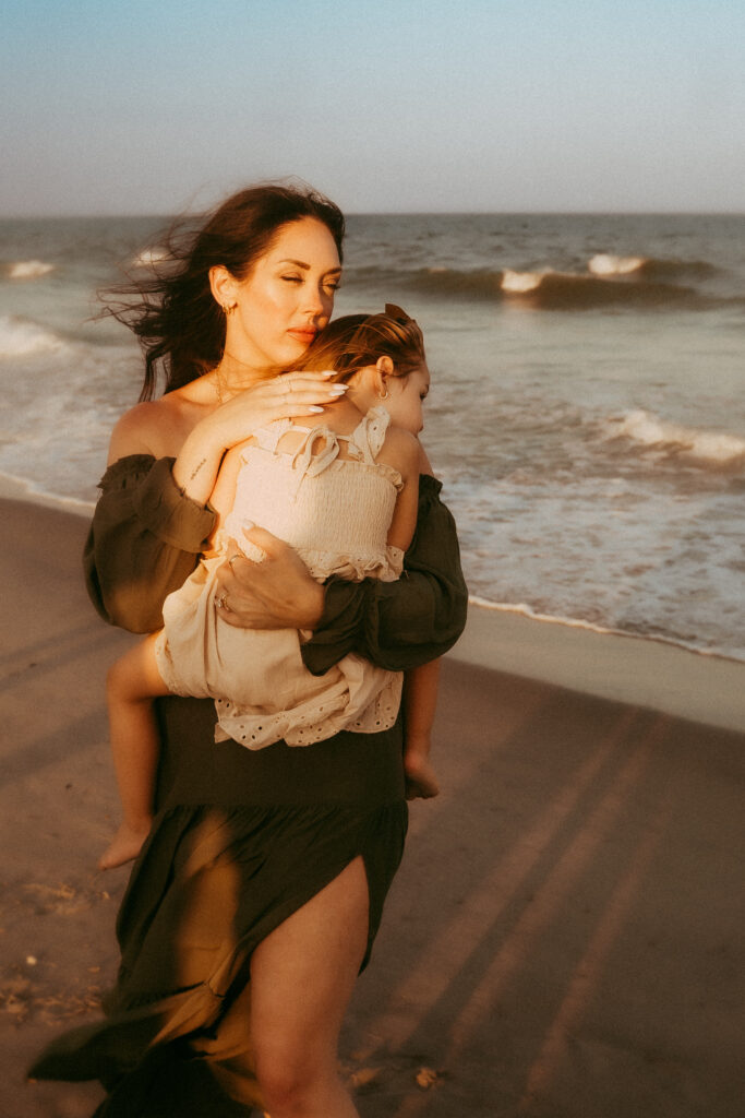 Mother hugging toddler daughter in Myrtle Beach SC sand dunes at sunset photographed by Moody Momma